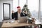 Emotional adult in Santa hat lifting hands while looking at computer screen