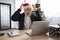 Emotional adult in Santa hat lifting hands while looking at computer screen