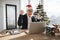 Emotional adult in Santa hat lifting hands while looking at computer screen