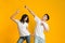 Emotional asian guy and girl dancing over yellow background