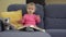 Emotional baby girl turn pages of book sitting on sofa with teddy bear friend