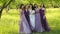 Emotional bride and bridesmaids talking and smiling. Caucasian girls in purple dresses posing outdoors.