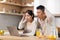 Emotional chinese spouses watching news online at kitchen, copy space