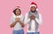 Emotional Christmas couple gesturing over pink background