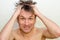 Emotional crazy caucasian man with bristles and shaggy hair, he holds head with hands, on white background