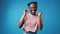 Emotional ecstatic young african woman celebrates success on blue background in studio