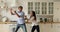 Emotional excited young caucasian family couple dancing in kitchen.