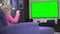 Emotional female child looking at green screen chroma key tv