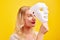 Emotional female person with white mask on yellow background. Internet fraud concept, anonymous, incognito, bipolar personality di