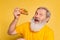 Emotional gray bearded man tasting pizza with cheese and tomatoes isolated on yellow studio background.