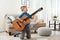 Emotional little boy playing guitar on floor