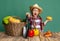 Emotional little girl, cheerful kid in image of farmer, gardener having fun with seasonal vegetables isolated on green