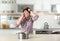 Emotional man calling plumber near table with saucepan under leaking water from ceiling