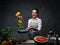 Emotional mature female chef tossing chopped vegetables from a pan