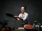 Emotional mature female chef tossing chopped vegetables from a pan