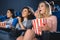 emotional multiracial women with popcorn watching film together