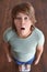 Emotional overweight boy standing on floor scales, above view