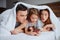 Emotional parents and daughter watching video on smartphone on bed