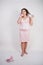 Emotional plump woman in pink dress talking and gossips on the Shoe like on the phone on a white Studio background