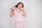 Emotional plump woman in pink dress talking and gossips on the Shoe like on the phone on a white Studio background