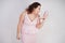 Emotional plump woman in pink dress talking and gossips on the Shoe like on the phone on a white Studio background