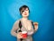 Emotional plus size girl with short hair stands in a sweater and holds a red Cup of tea with polka dots and sweet