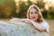 Emotional portrait of a cheerful  blonde girl in a countryside landscape with hay rolls in sunset light