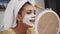 Emotional portrait of a happy and calm beautiful naked girl with a blue clay cosmetic mask on half of her face, looking