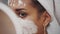 Emotional portrait of a happy and calm beautiful naked girl with a blue clay cosmetic mask on half of her face, looking