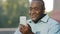 Emotional senior African American man making video call looking at smartphone camera talking on cellphone. Black male