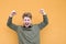 Emotional student raised his hands from happiness against the background of an orange wall