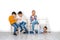 Emotional studio shot of children, girls and three boys sitting on chairs waiting. Older boys play armwrestling, the younger boy