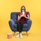 Emotional teenage girl with 3D glasses, popcorn and beverage sitting in armchair during cinema show