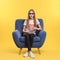 Emotional teenage girl with 3D glasses and popcorn sitting in armchair during cinema show