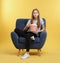 Emotional teenage girl with popcorn sitting in armchair during cinema show