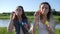 Emotional teenage girls make soap bubbles and laugh near lake