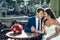 Emotional wedding portrait of the happy newlyweds holding hands and touching heads while sitting at the wooden table