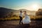 Emotional wedding shot of the happy glamour newlywed couple dancing on the road during the sunset. Beautiful nature view