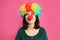 Emotional woman with rainbow wig and clown nose on background. April fool`s day