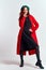 Emotional woman in a red coat and with a hat in full growth on a light background black boots pose model