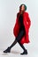 Emotional woman in a red coat and with a hat in full growth on a light background black boots pose model