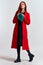 Emotional woman in a red coat and with a hat in full growth on a light background black boots pose model