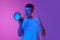 Emotional young man shouting in megaphone against gradient pink purple background in neon light. News, sales