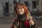 An emotional young woman of 20-25 years old with glasses, dyed red hair and a little overweight against the background of the city