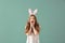 Emotional young woman with Easter bunny ears on color background