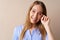 Emotional young woman heard a joke laughing to tears against beige background