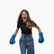 Emotionaly girl with braces in blue boxing gloves confidently going to victory , isolated