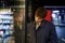 Emotionless Caucasian woman with short hair examines shop window standing on street in evening