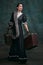 Emotions. Beautiful woman in image of Anna Karenina with retro suitcases over vintage dark green background. Concept of