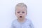 Emotions. Surprised toddler against wall. Close-up portrait of funny open-mouthed little kid